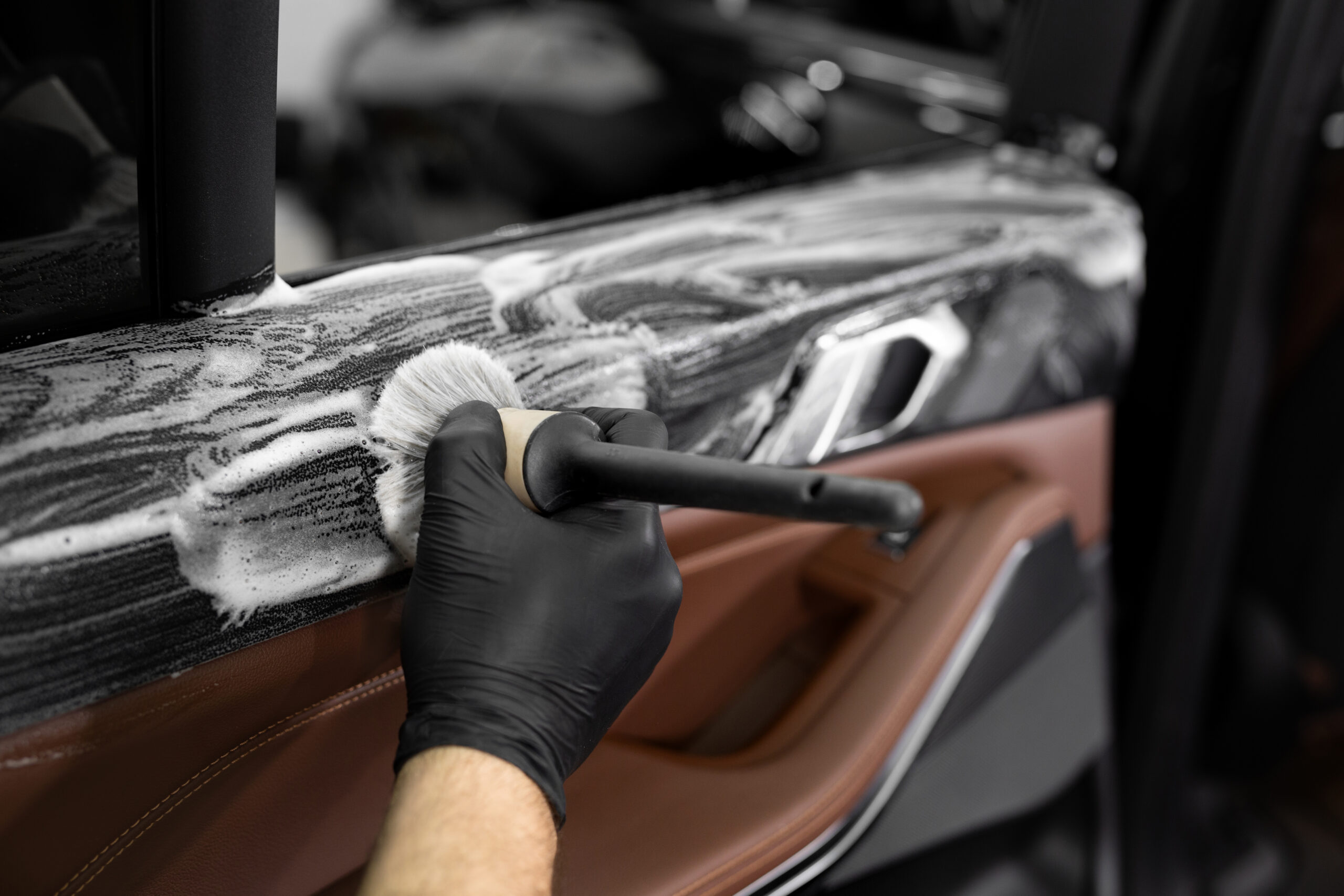 Detailer cleaning a car door panel
